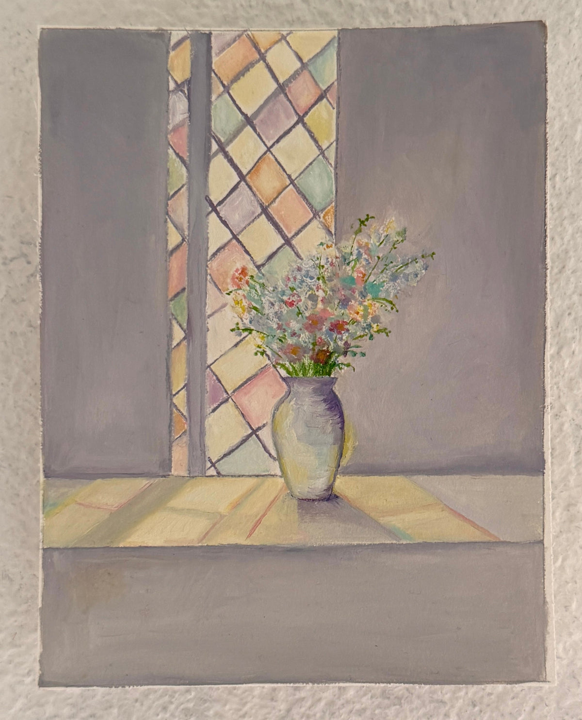 A small still life painting hanging on a textured off-white wall, depicting a vase of flowers placed in front of a window with a diamond-patterned pane.